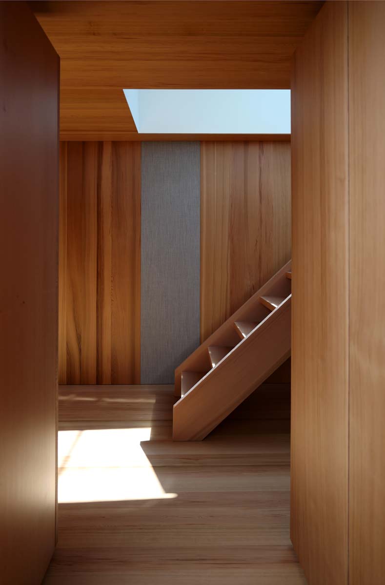 Interior space with wooden walls and floor, a skylight above, and a small wooden staircase against the back wall.